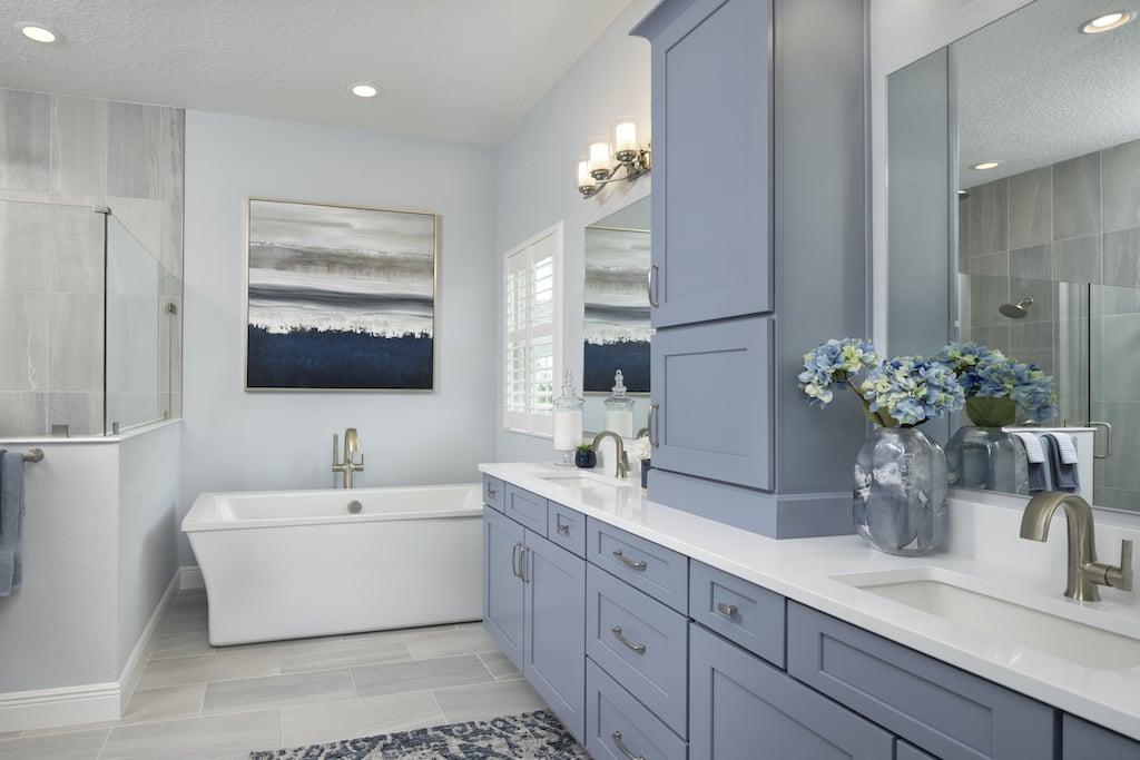 Bathroom with blue cabinets, large bathtub, and dual sinks