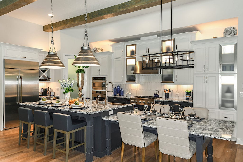 Modern kitchen whwith modern pendant lights, island with seating, and dining table next to it